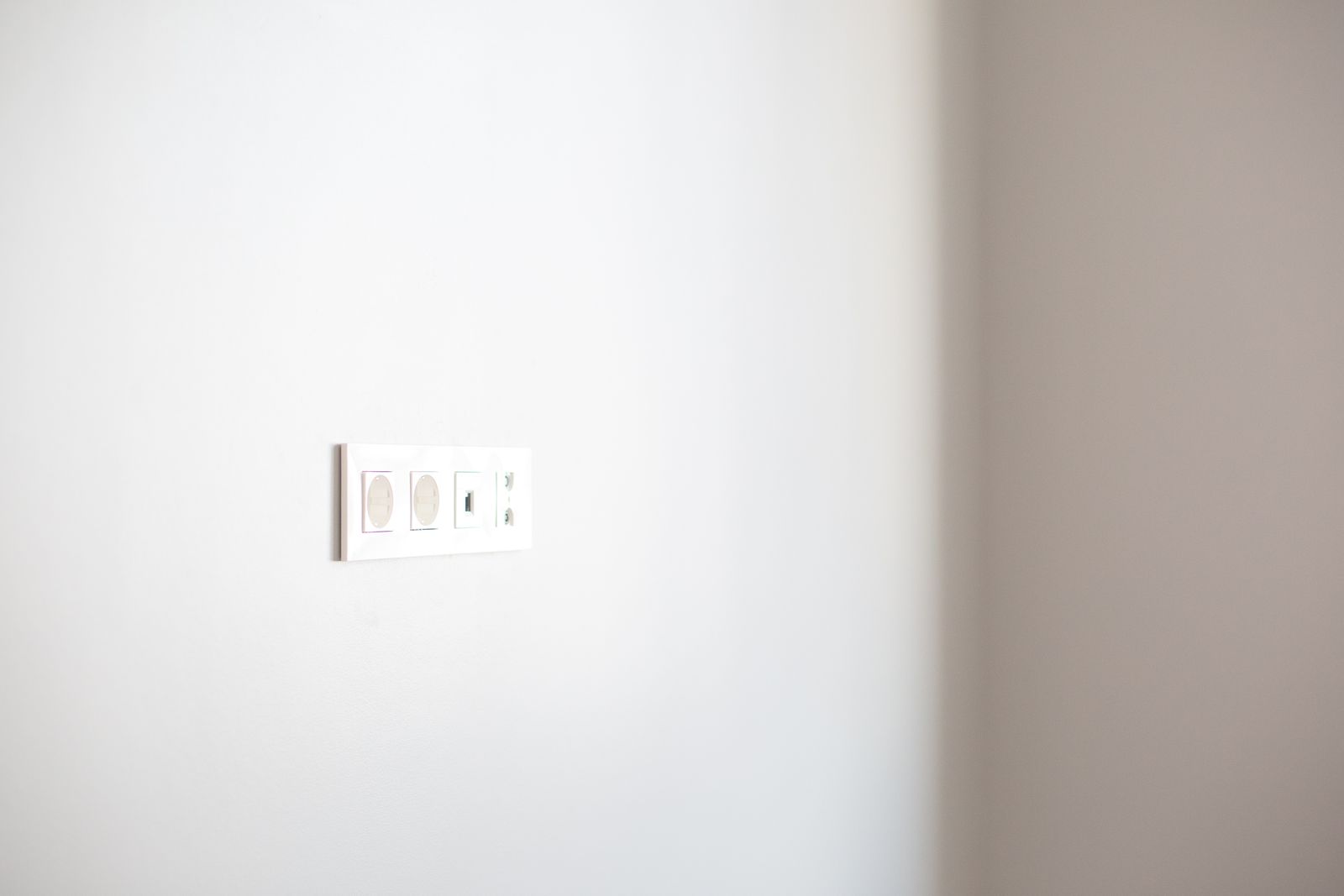 Schlichte weiße Wandsteckdose, sauber in eine helle Wand eingelassen — moderne Elektroinstallation